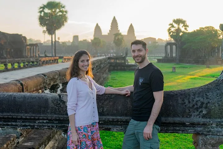 Two travelers on the stone causeway with the Angkor Wat towers behind them on an Angkor sunrise tour by Vespa or tuk-tuk