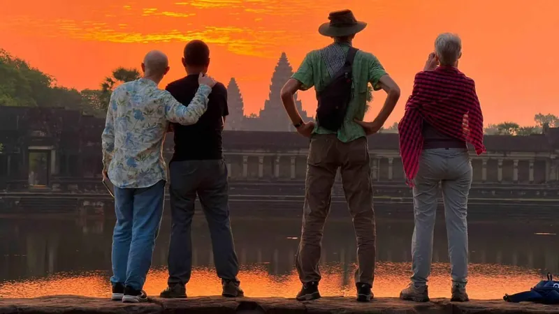 Four travelers watching an orange dawn over the Angkor Wat towers on a private tuk-tuk Angkor Wat tour