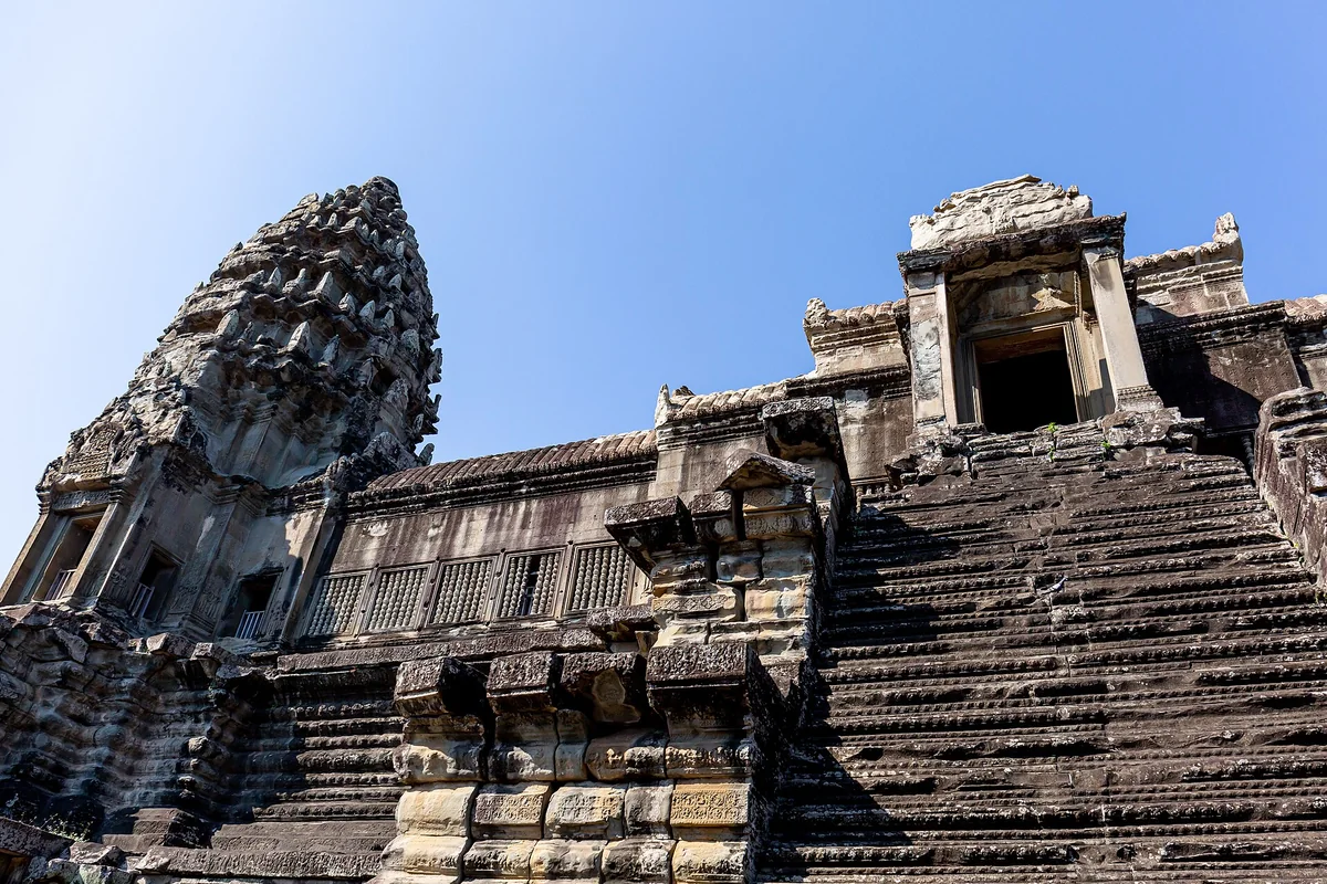 The steep stone stairs climbing to a central tower of Angkor Wat under a blue sky, seen on Angkor Wat tours from Siem Reap