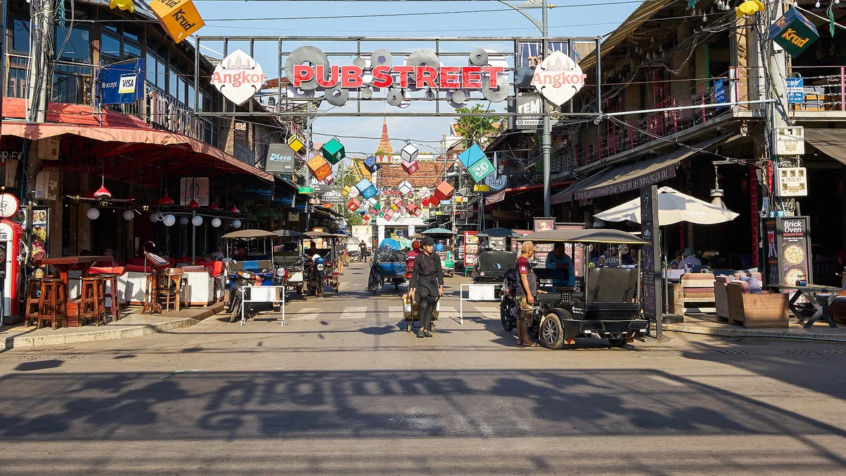 The Pub Street sign over the road in Siem Reap, with tuk-tuks and cafes below, seen on Angkor Wat tours from Siem Reap