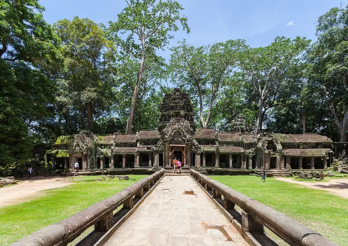 The paved approach and entrance gallery of Ta Prohm among tall trees, seen on Angkor Wat tours from Siem Reap