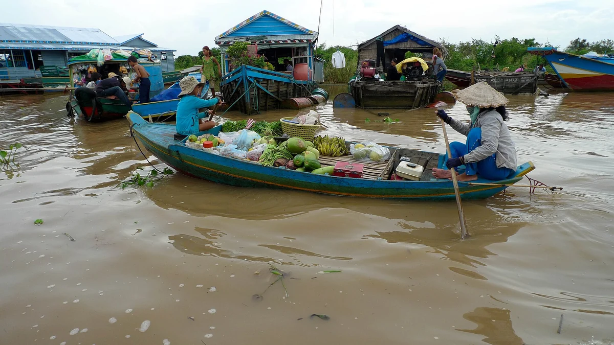 A boat selling produce beside floating houses on Tonle Sap lake, seen on Angkor Wat tours from Siem Reap
